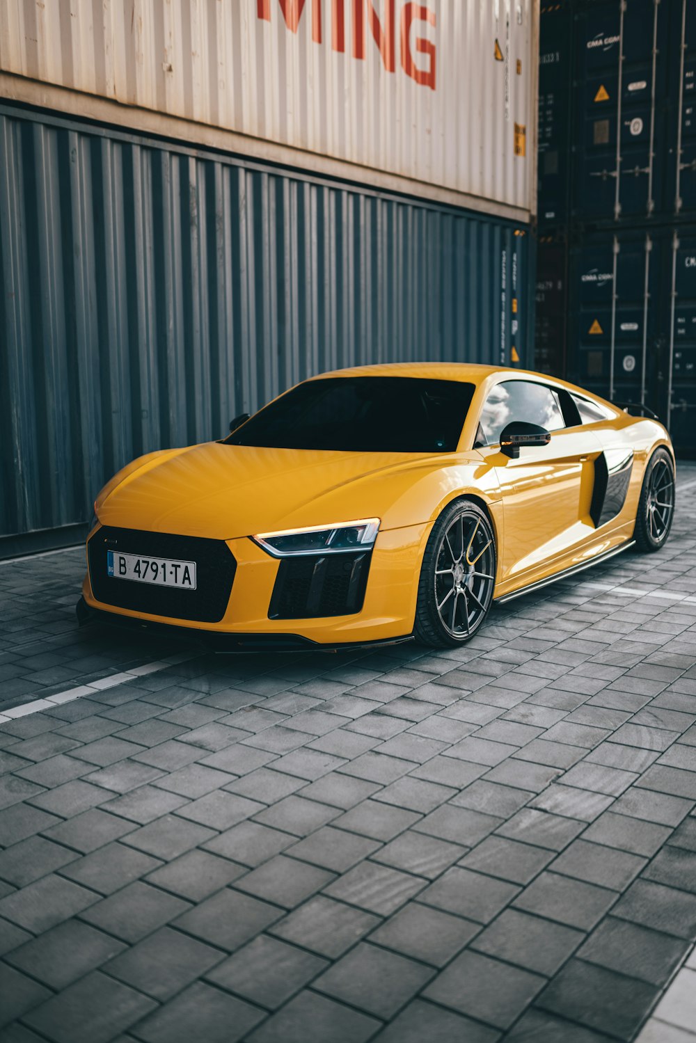 lamborghini aventador amarelo estacionado perto de parede cinza