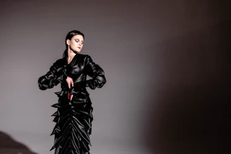 A dramatic portrait of a model wearing an avant-garde dark gown inspired by tarot cards, posing against a high-contrast backdrop