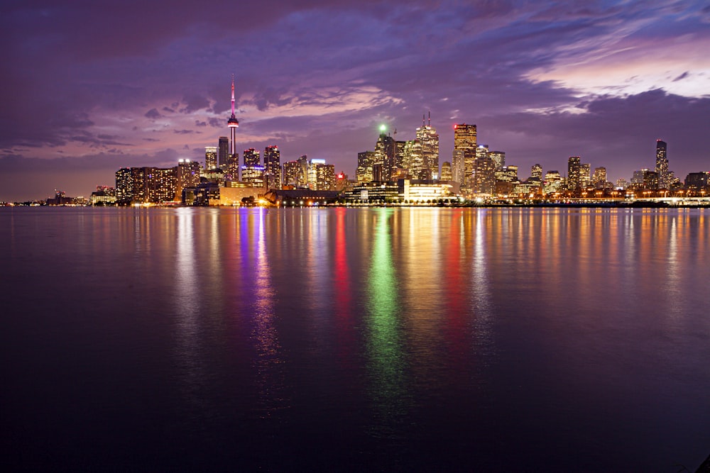 city skyline across body of water during night time