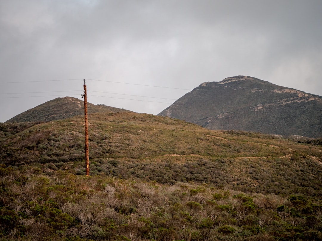 green grass field near mountain under white clouds during daytime