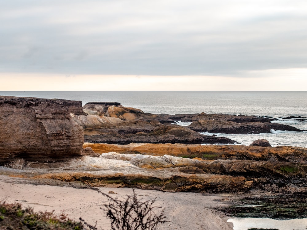 brown rock formation near body of water during daytime