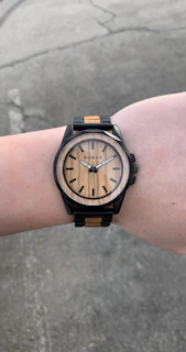 Close-up of terravibe’s minimalist watch and leather bracelet on a man’s wrist against a concrete wall