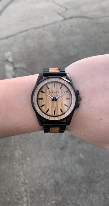 Close-up of terravibe’s minimalist watch and leather bracelet on a man’s wrist against a concrete wall