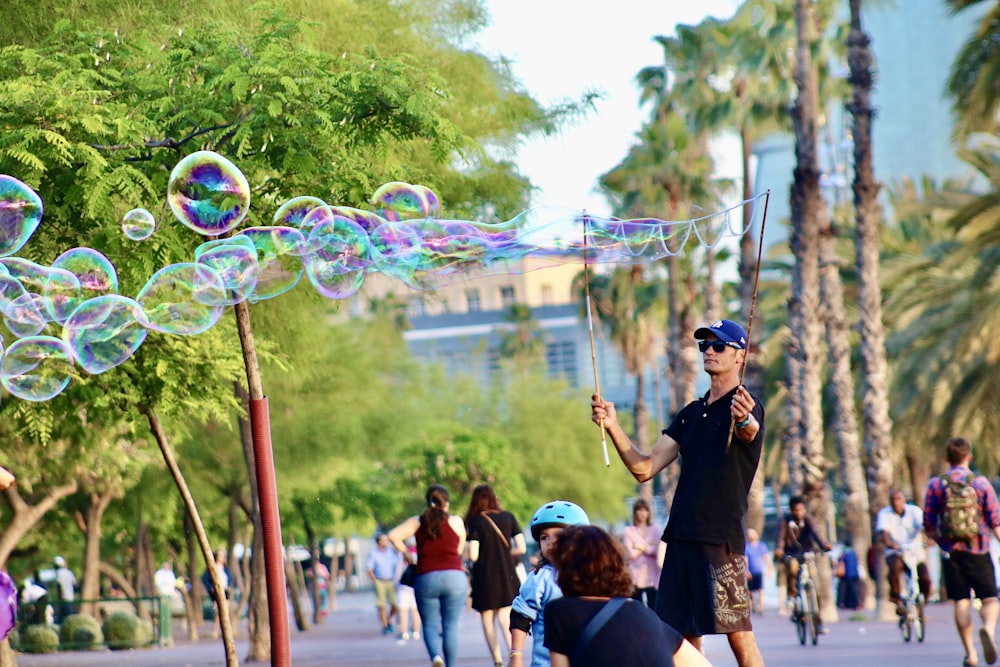 Hombre con camiseta negra jugando a las burbujas durante el día