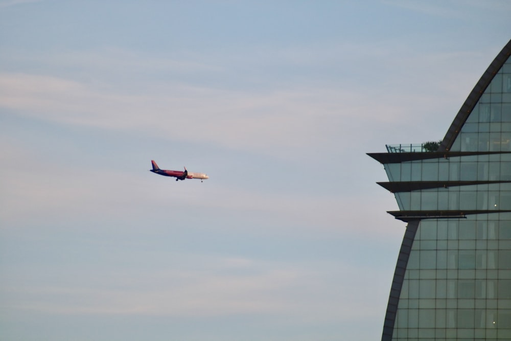 red and white airplane flying over the building