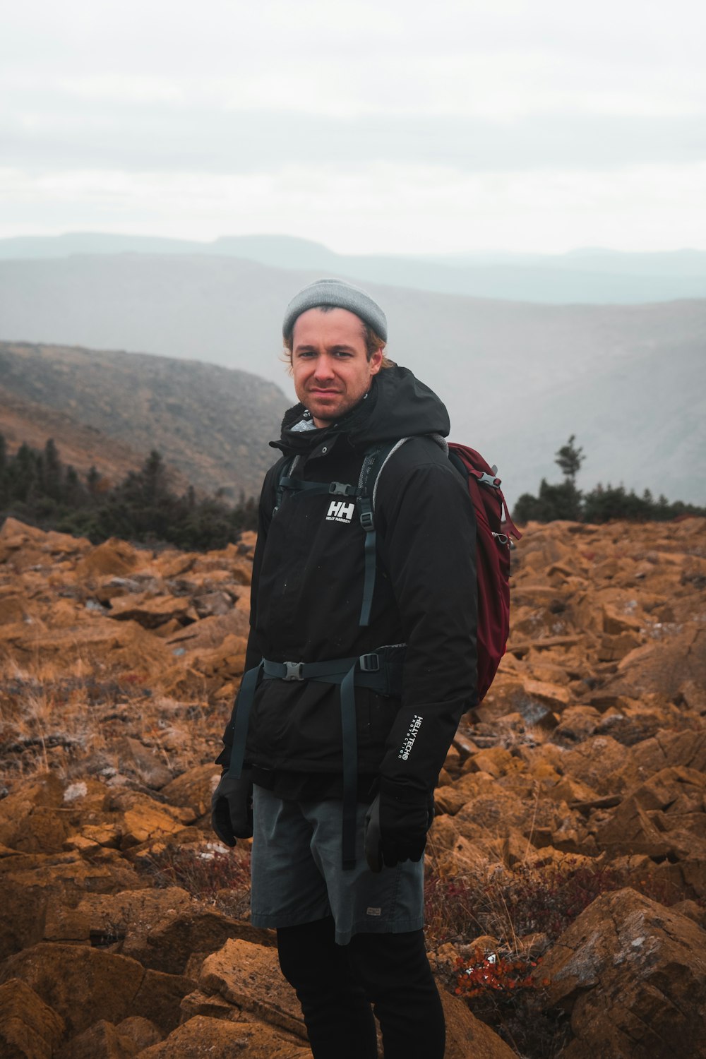 man in black jacket and black pants with black backpack standing on brown rocky mountain during