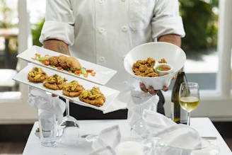 person in white dress shirt holding white ceramic bowl with food