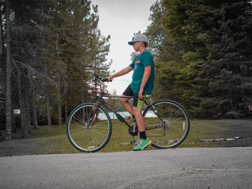 man in red shirt riding on bicycle on road during daytime