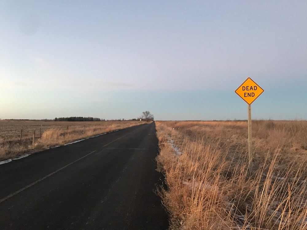 Carretera de asfalto negro entre campos de hierba marrón durante el día