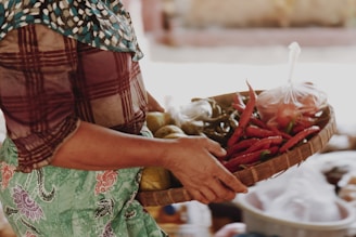 A smiling farmer holding a basket of freshly harvested spices.