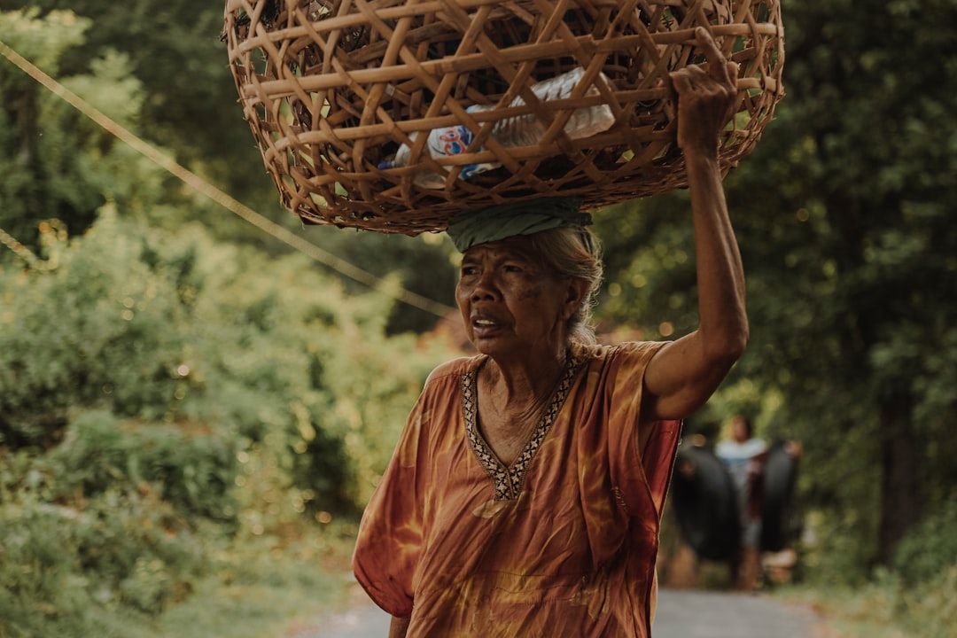 woman in orange and blue sari dress holding brown woven basket