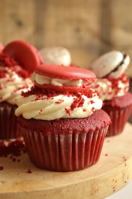 Freshly baked red velvet cupcakes with creamy white frosting and a sprinkle of red crumbs