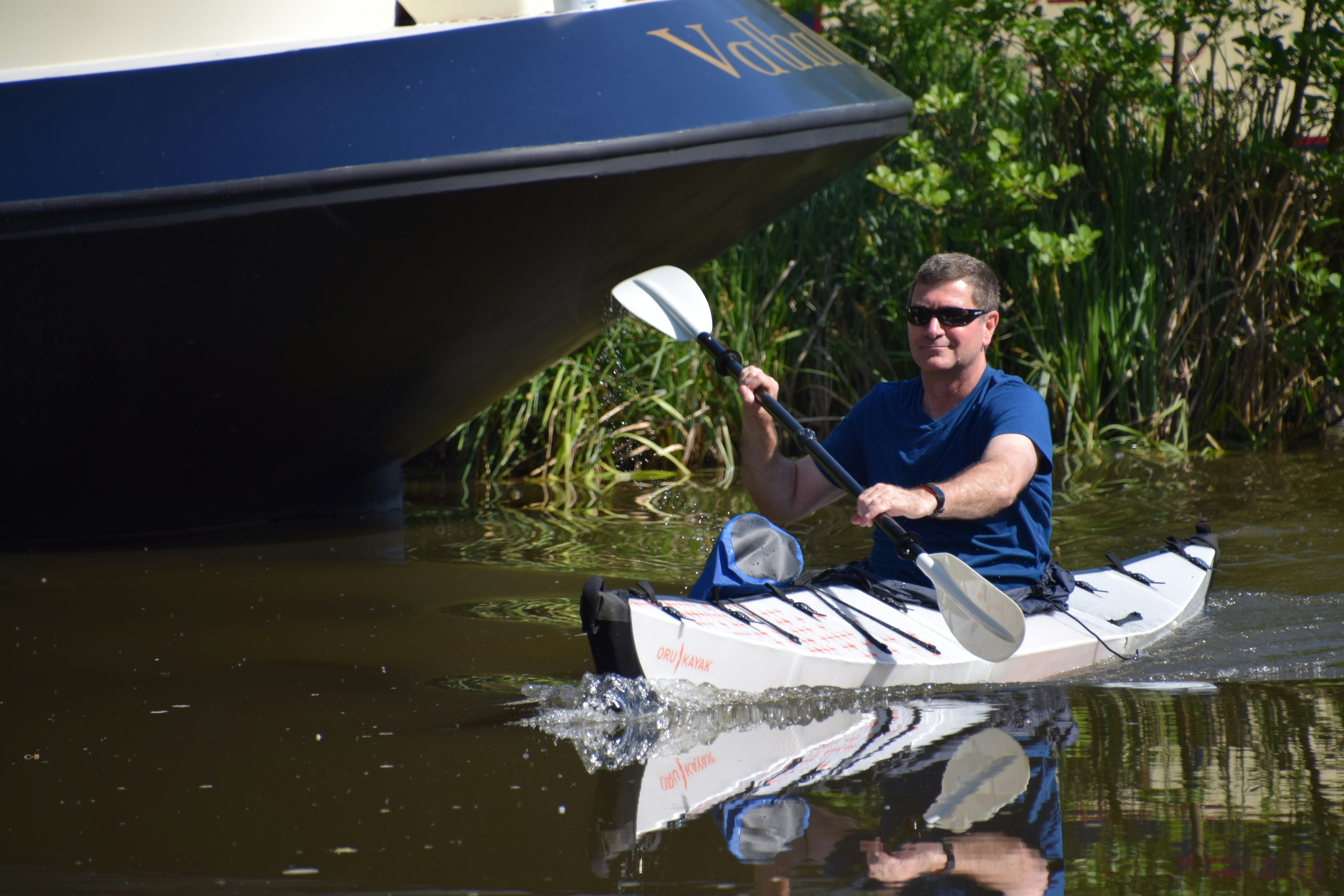 homme en chemise bleue équipant un kayak blanc et rouge
