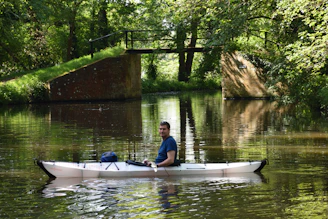 woman in blue shirt riding on blue kayak on river during daytime