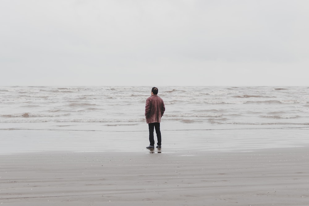 man in brown jacket walking on beach during daytime