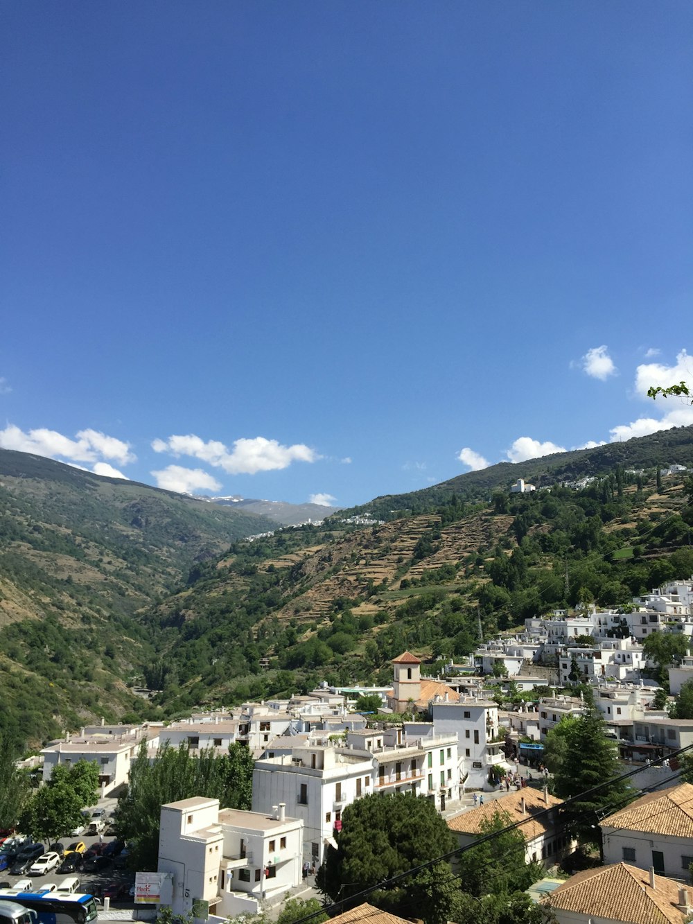Edifici in calcestruzzo bianco e marrone sulla montagna verde sotto il cielo blu durante il giorno
