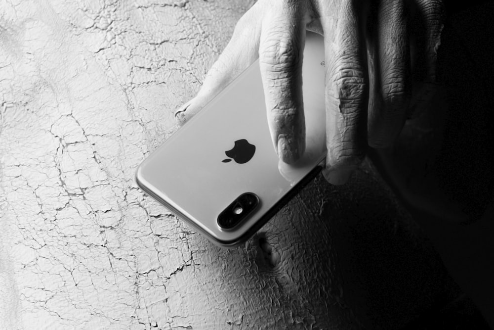 person holding iphone on black leather textile