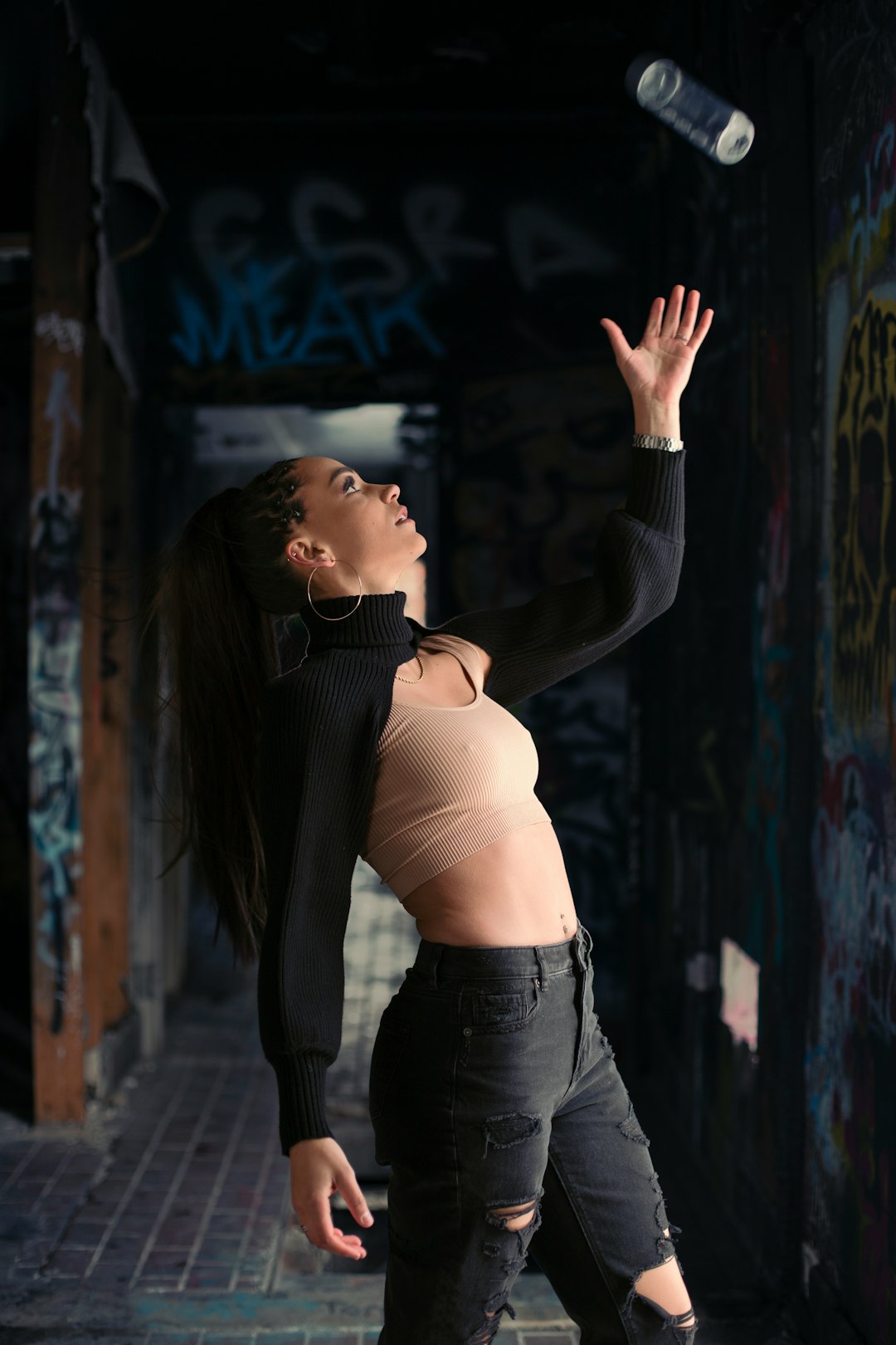 woman in brown sports bra and black denim jeans standing and raising her right hand