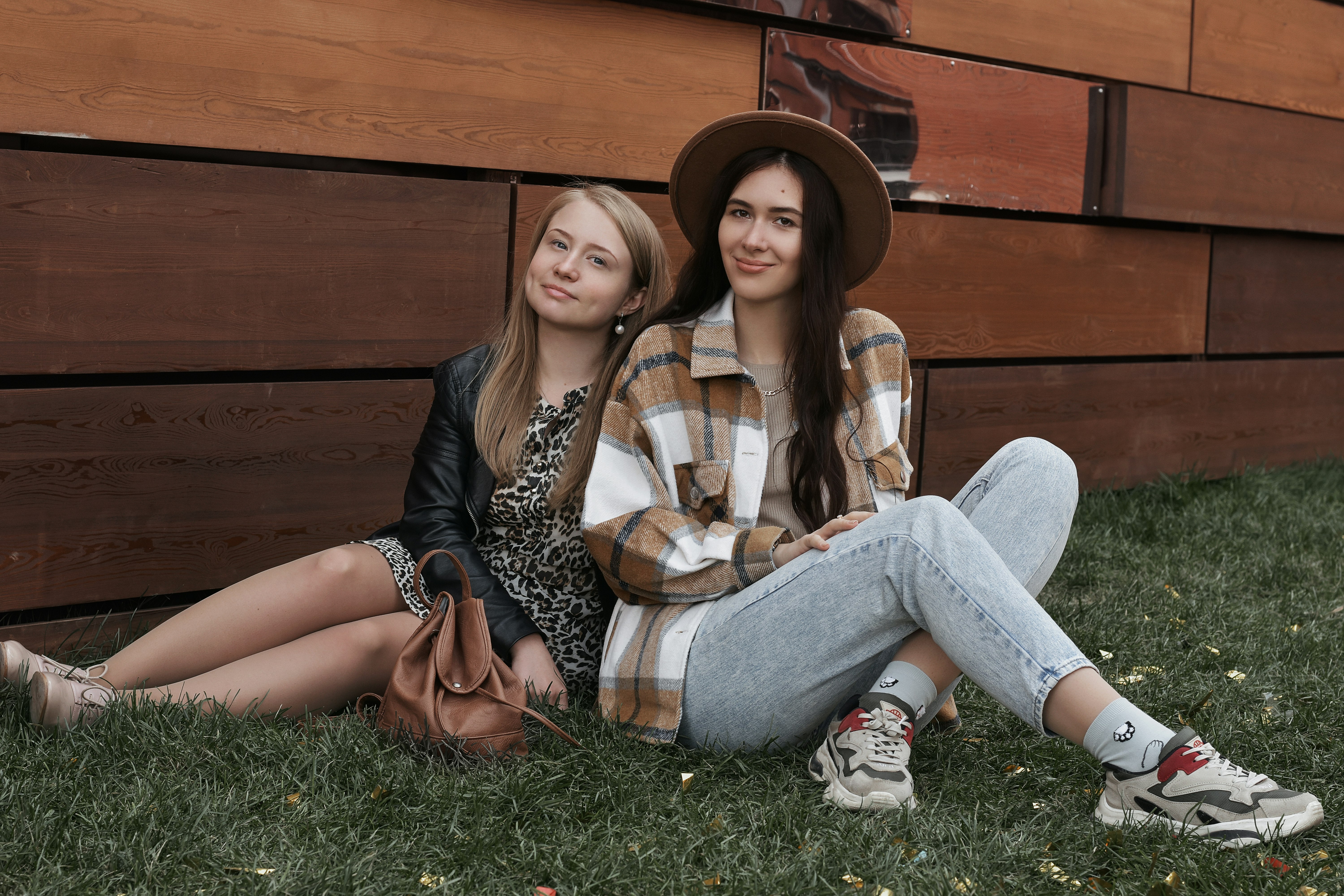 woman in white and black leopard print shirt and blue denim jeans sitting on green grass