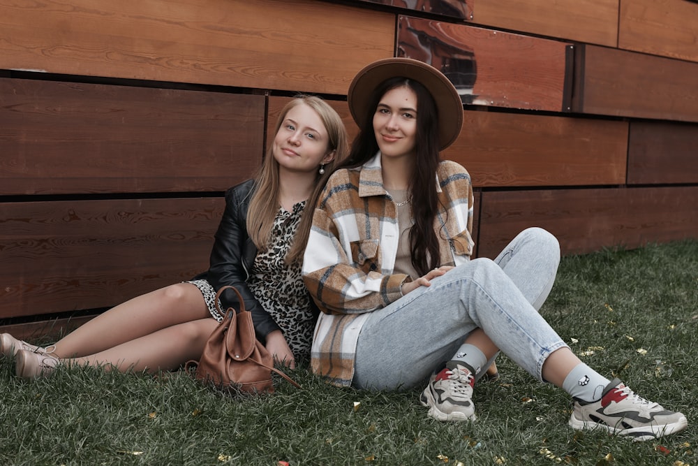 woman in white and black leopard print shirt and blue denim jeans sitting on green grass