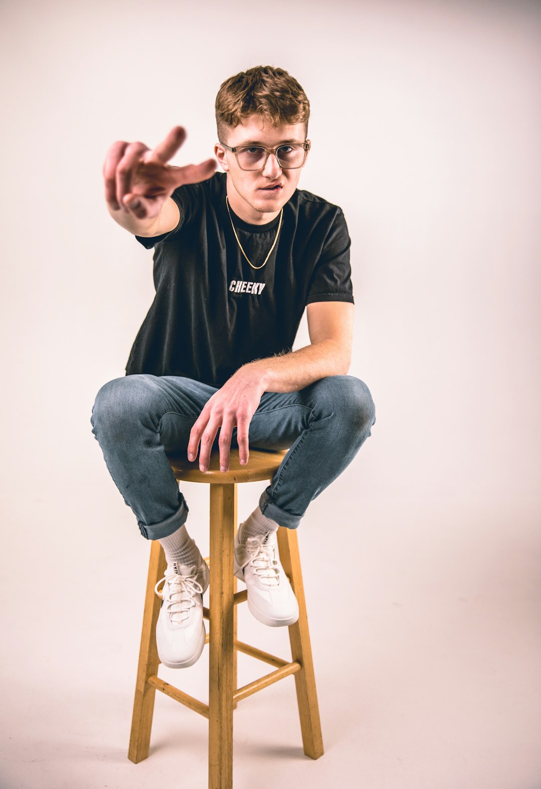 man in black crew neck t-shirt and blue denim jeans sitting on brown wooden seat