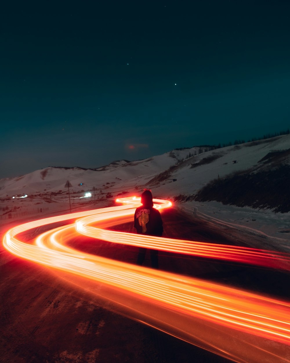 pessoa em jaqueta vermelha em pé na estrada durante a noite