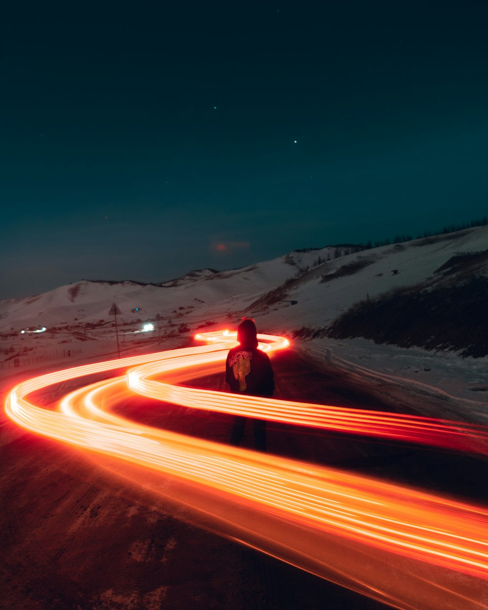 person in red jacket standing on road during night time