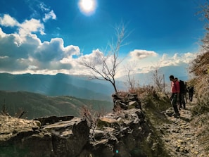 A joyful traveler walking along a mountain trail under a clear blue sky