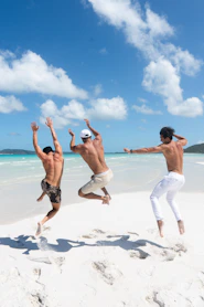 2 women in white shorts running on white sand beach during daytime