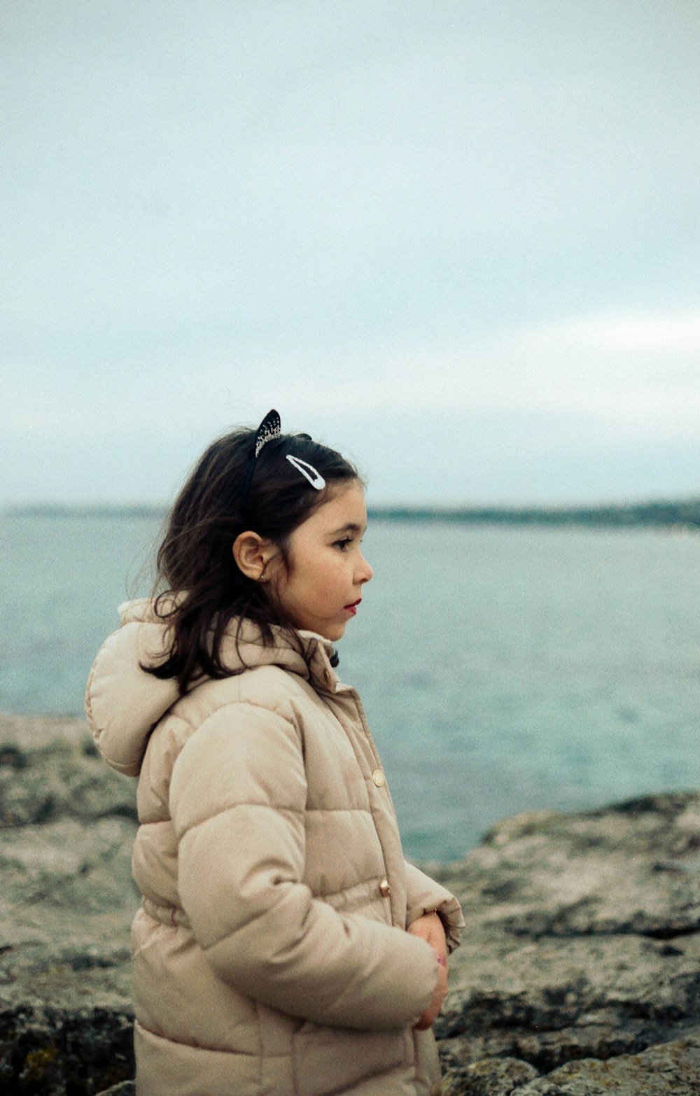 woman in brown coat standing near body of water during daytime