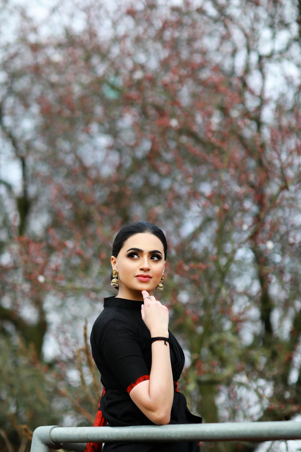 woman in black turtleneck long sleeve shirt standing near cherry blossom tree during daytime