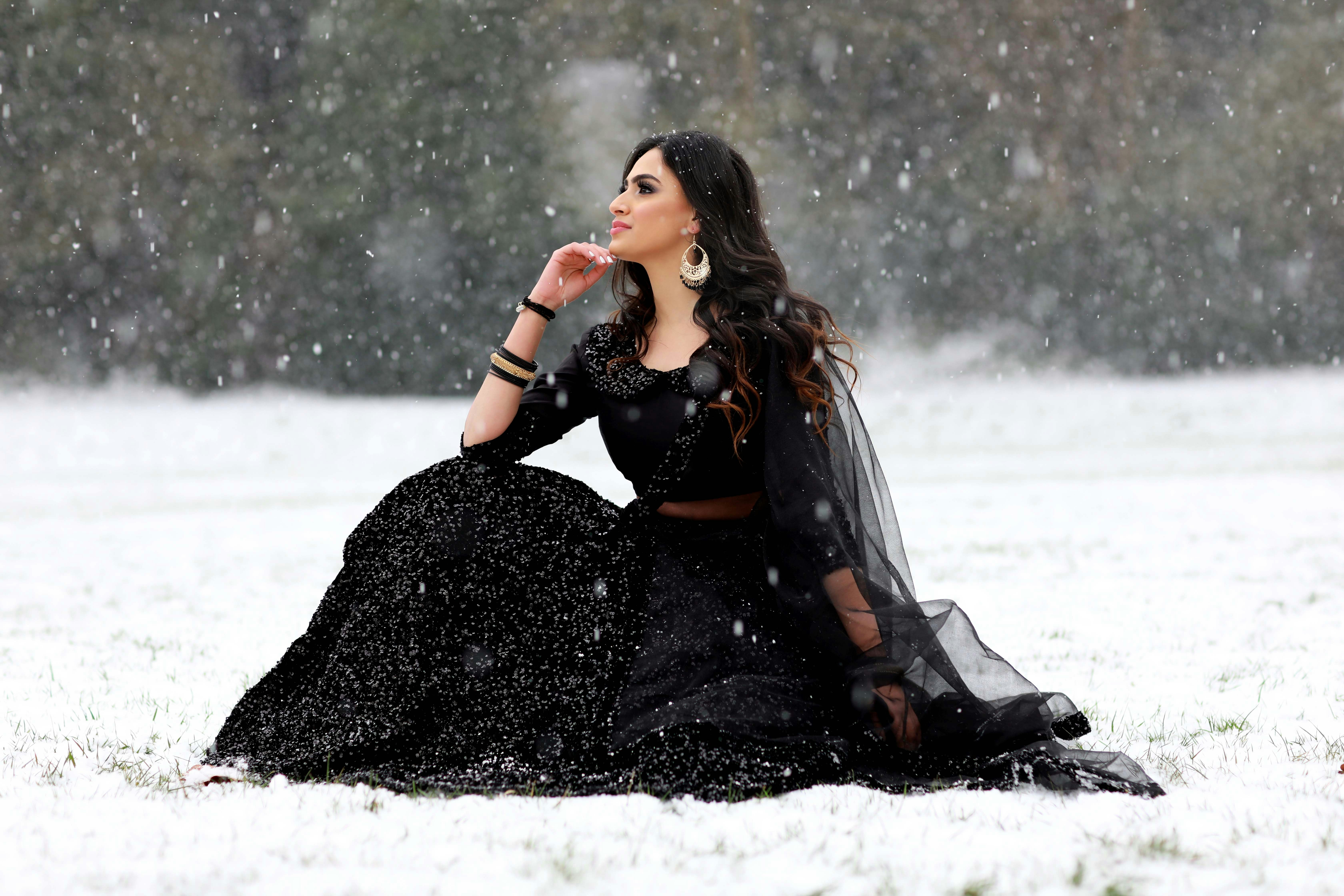 woman in black leather jacket sitting on snow covered ground
