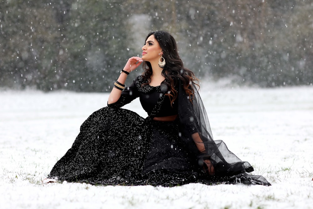 woman in black leather jacket sitting on snow covered ground