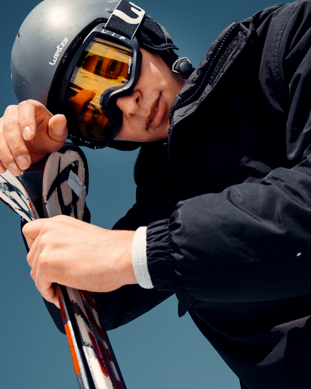 man in black jacket holding orange and black helmet