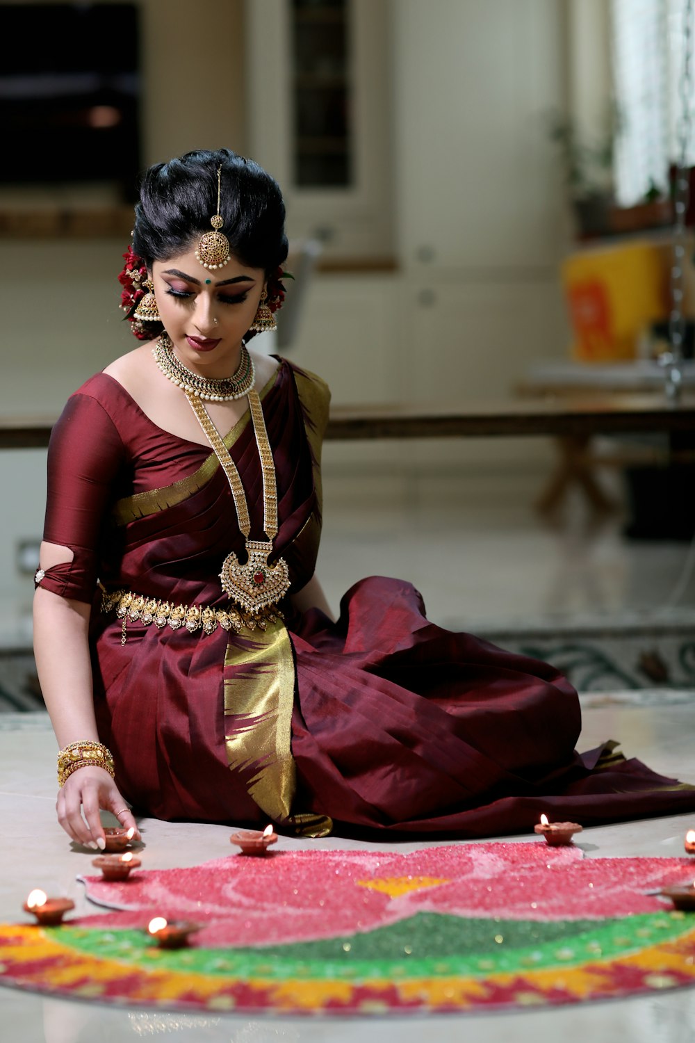 woman in red and gold sari sitting on red textile