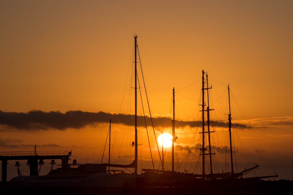 silhouette of sail boat on sea during sunset