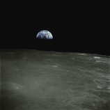 Earth rising over the moon’s horizon, a blue and white marble in the blackness of space.