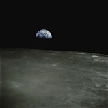 Close-up of the moon’s surface with Earth rising in the background.