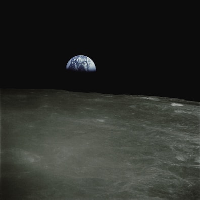 Earth rising over the moon’s horizon, a blue and white marble in the blackness of space.