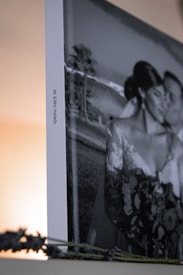 A framed black and white photograph features a couple in wedding attire, embracing closely. The image is partially visible with a focus on the side, which displays the names Mr. & Mrs. Hurtado. Lavender sprigs are placed in the foreground.