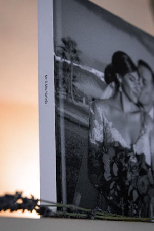 A framed black and white photograph features a couple in wedding attire, embracing closely. The image is partially visible with a focus on the side, which displays the names Mr. & Mrs. Hurtado. Lavender sprigs are placed in the foreground.