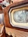 A vintage television set featuring a wooden frame and a black and white test pattern displayed on its screen. The image captures the details of the retro design, including the textured wood and intricate knobs. Part of a decorative colorful textile is visible in the background.