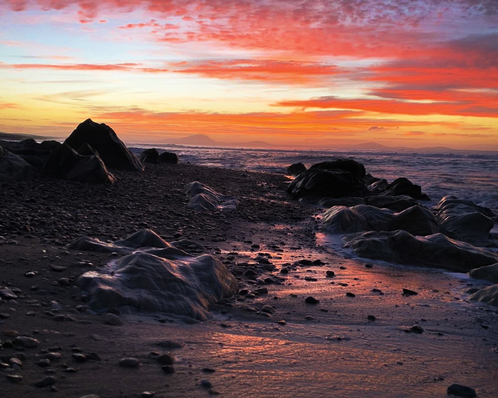 Roches noires sur la plage au coucher du soleil