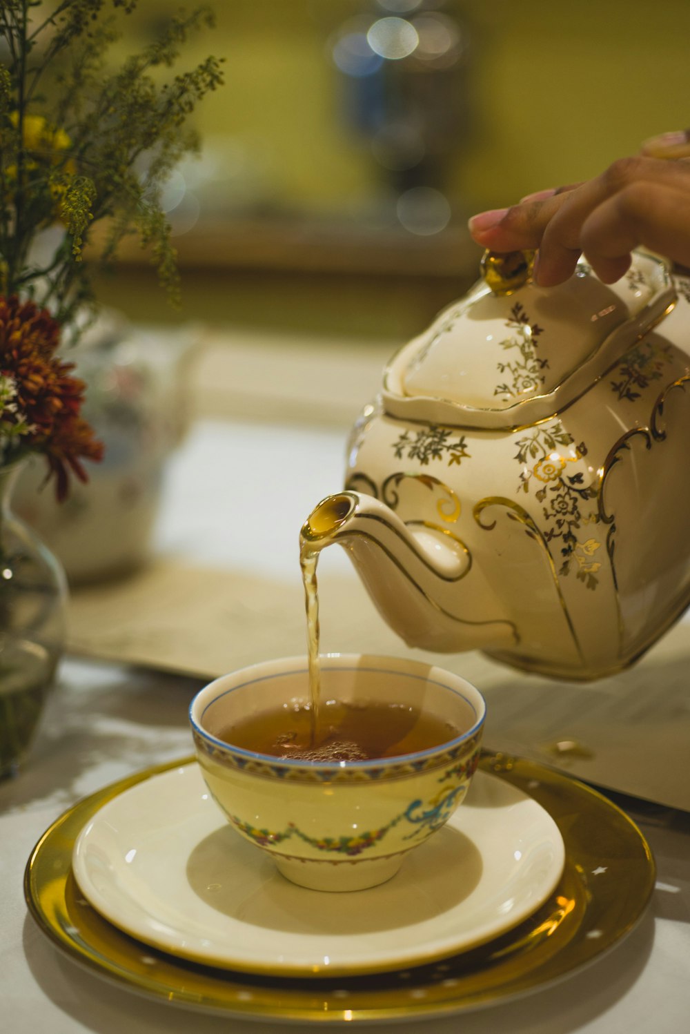 person pouring tea on white ceramic teapot