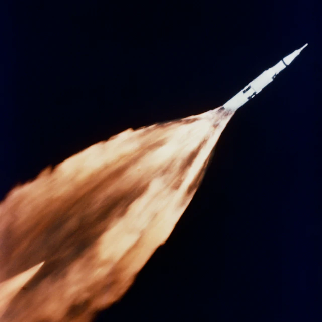 A Saturn rocket lifting off with a long trail of flames during launch