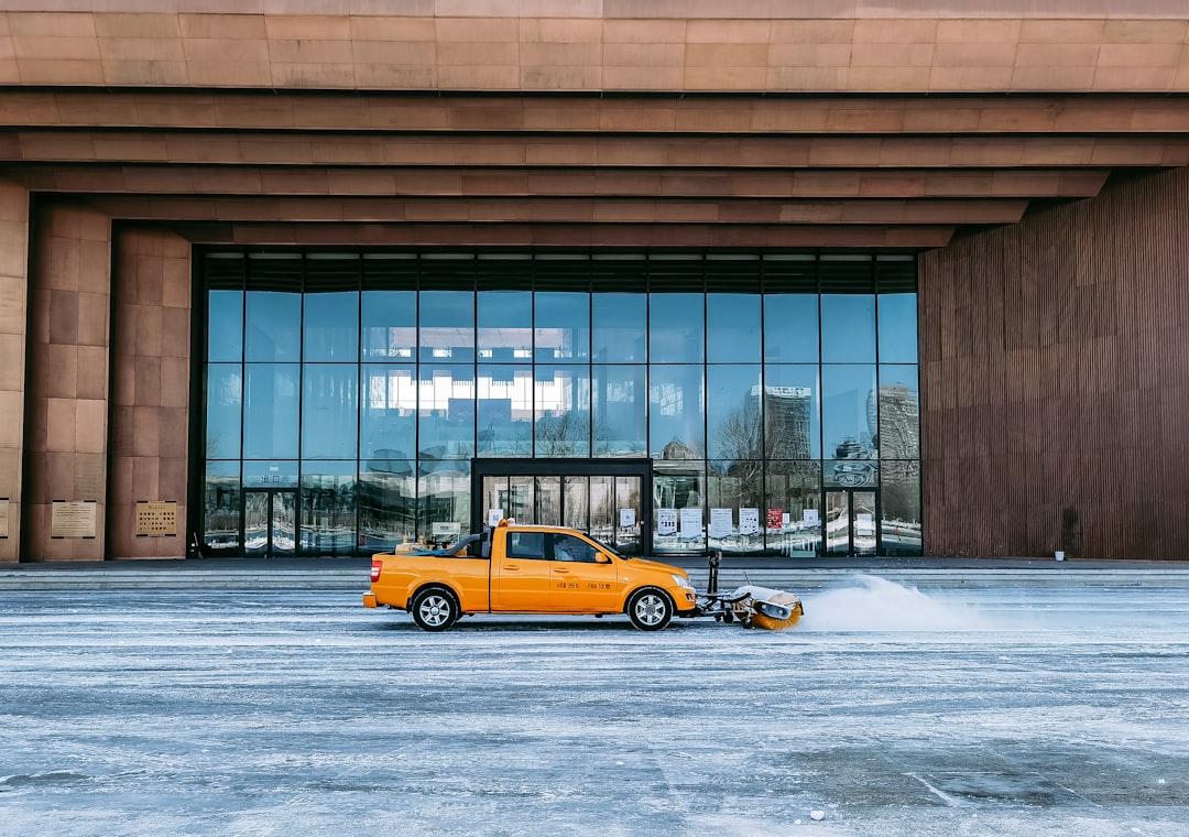 yellow taxi cab on snow covered road near building during daytime