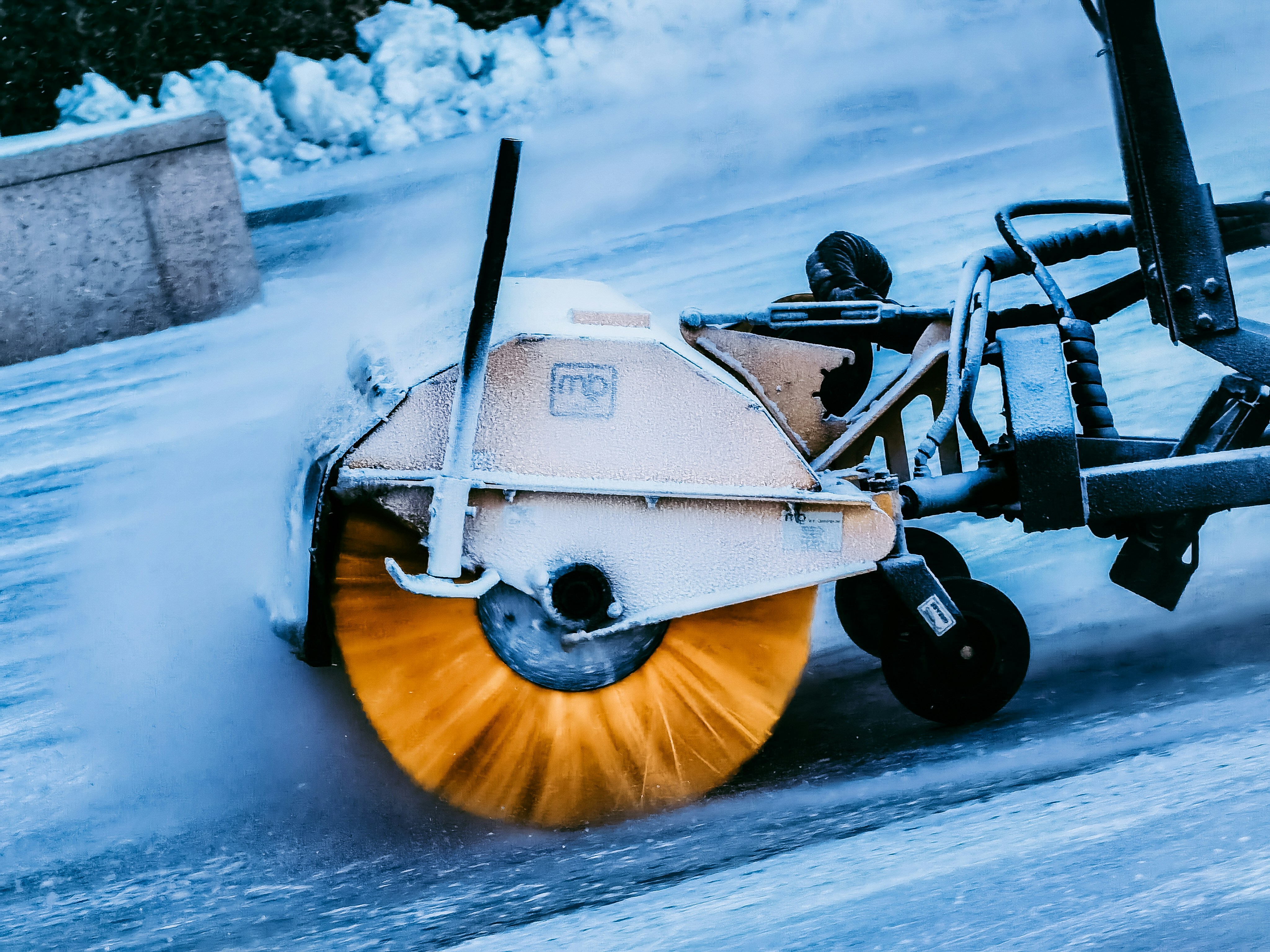 Ein professionelles Schneeräumfahrzeug räumt eine verschneite Zufahrt zu einem Gewerbeobjekt.