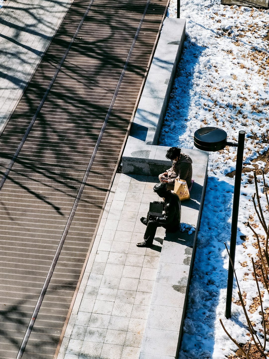man in black jacket sitting on bench during daytime