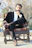 man in black suit sitting on brown wooden armchair