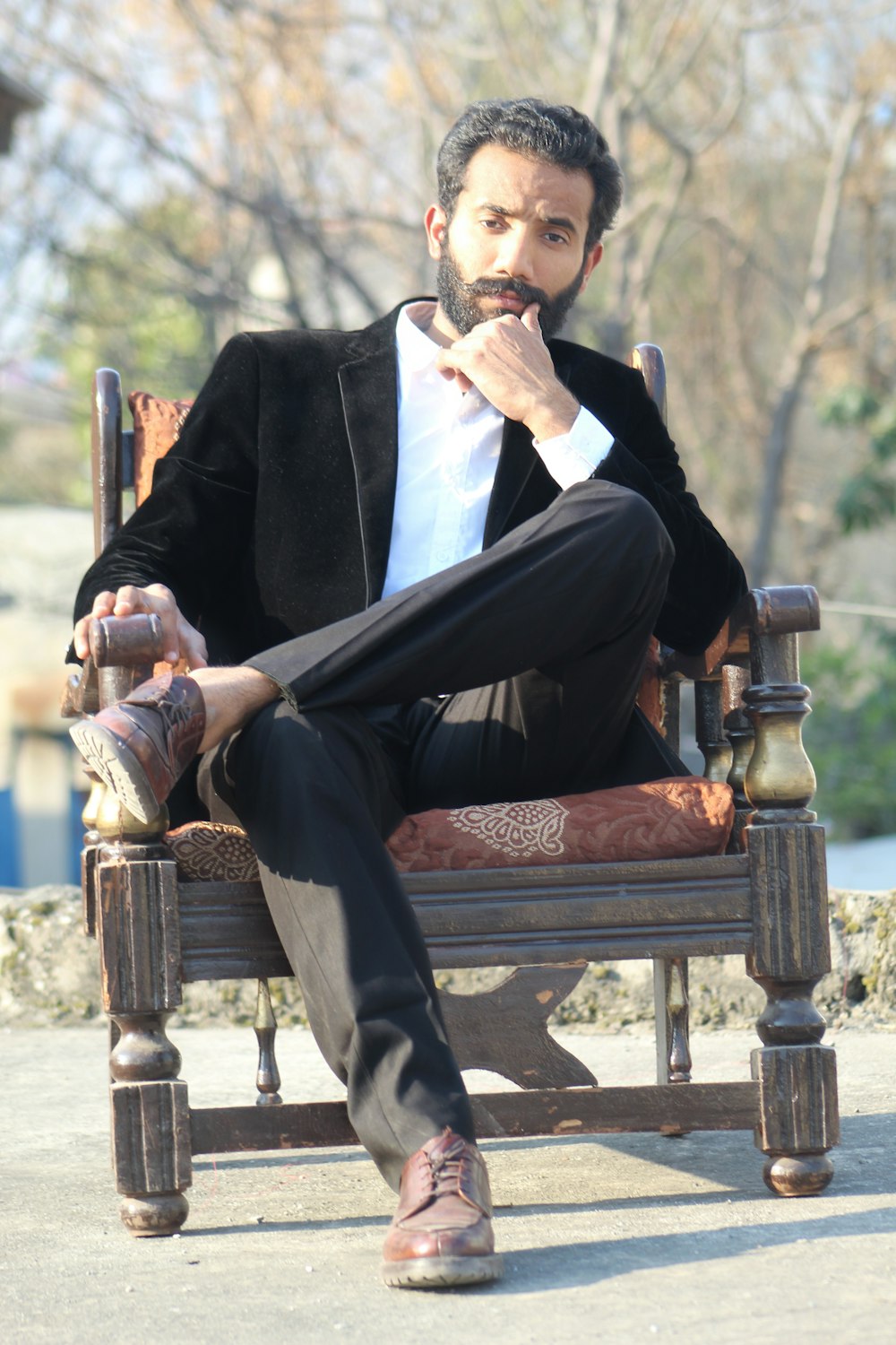 man in black suit sitting on brown wooden armchair